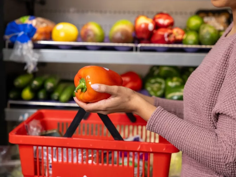 A customer holds a pepper at the grocery store (USDA photo) snap wic grocery shopping food cpi produce.jpg